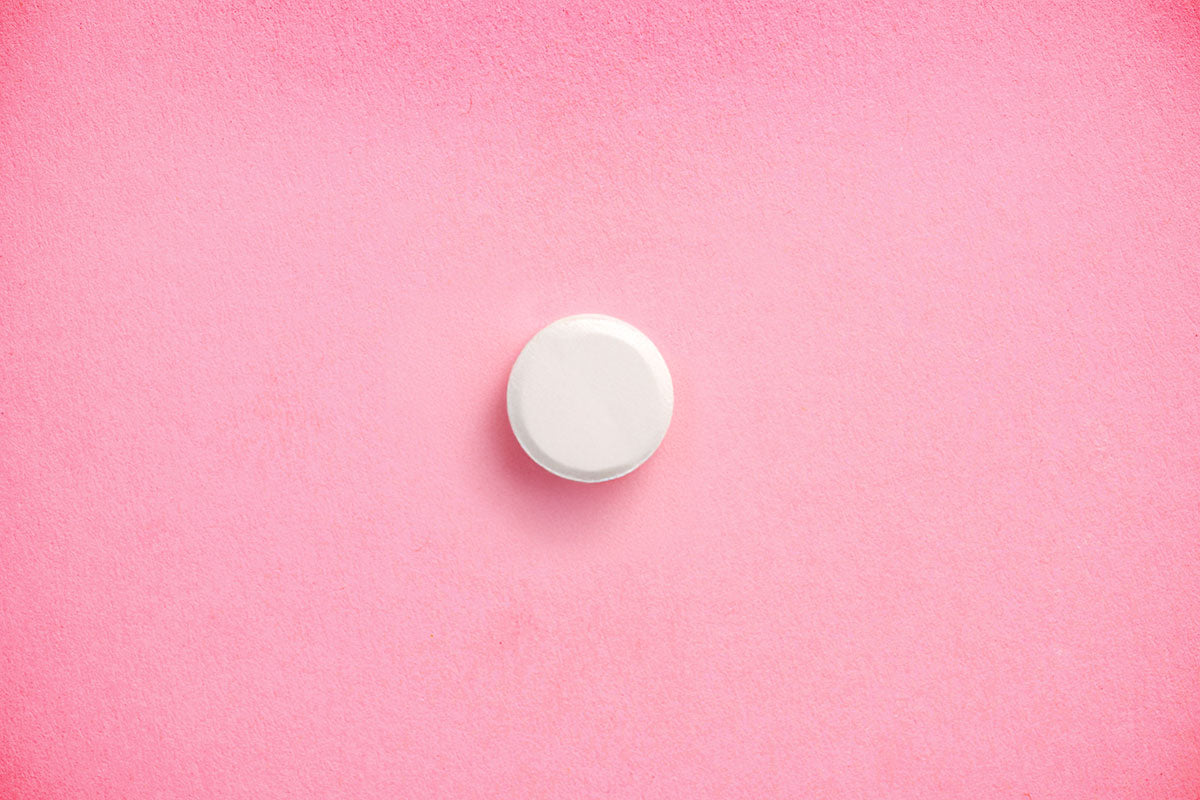 A white pill on a pink background
